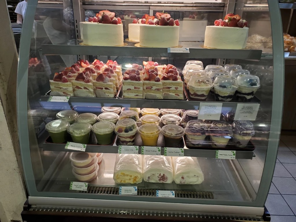 Refrigerated display case with whole cakes, slices, and cup desserts